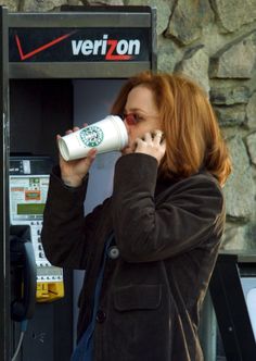 a woman drinking from a cup while using a verizon machine