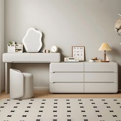 a white dresser sitting on top of a wooden floor next to a mirror and lamp