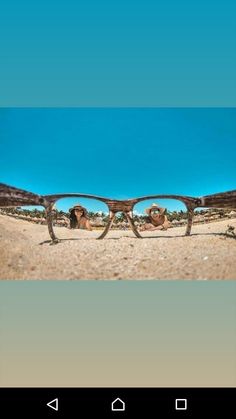 two people are seen through the reflection of their sunglasses on the beach in front of blue skies