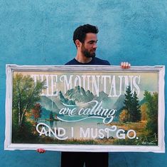 a man holding up a sign that says tea mountains are calling and i must go