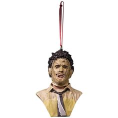 a creepy mask hanging from a red string on a white background with the image of a man's head wearing a tie