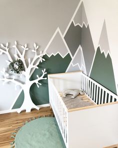 a baby's room with mountains painted on the wall and a white crib