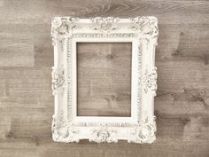 an old white frame hanging on a wooden wall with wood planks in the background