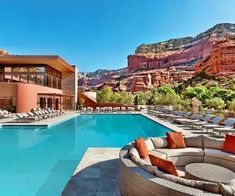 an outdoor swimming pool with chaise lounges and mountains in the background