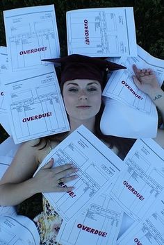 a woman laying in the grass with lots of papers on her head