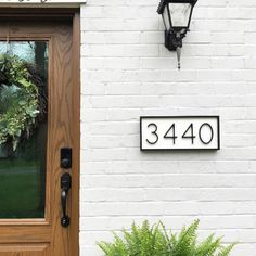 a house number sign next to a door with a wreath on the front and side