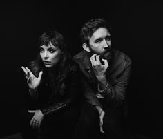 black and white photograph of two people sitting next to each other with their hands on their chins