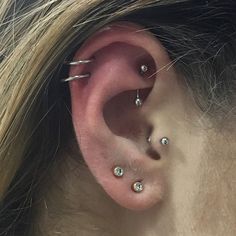 a woman's ear with three piercings on the top and bottom of it