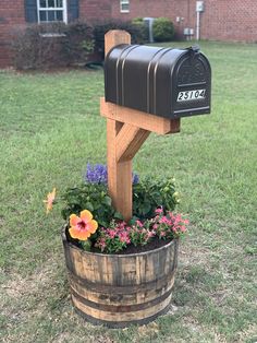 a mailbox sitting on top of a barrel filled with flowers