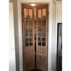 an open wooden door in a kitchen with white walls and wood trimming on the doors