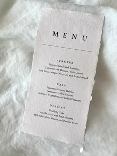 a white menu card sitting on top of a bed