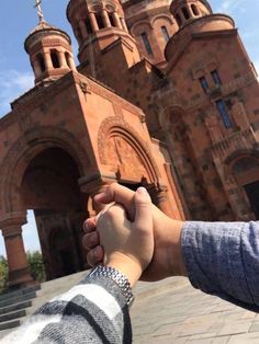 two people holding hands in front of an old building with steeples on the top