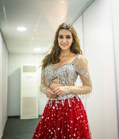 a woman in a red and silver dress posing for the camera with her hands on her hips