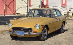 an old yellow car parked in front of a building