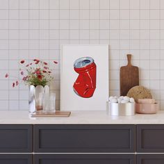 a red can is on the counter next to some vases and other items in front of a white tiled wall