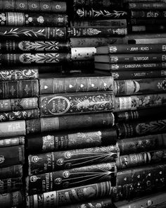 a stack of books sitting next to each other on top of a wooden table in black and white