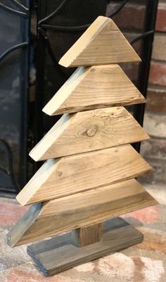 a small wooden christmas tree sitting on top of a table next to a fire place