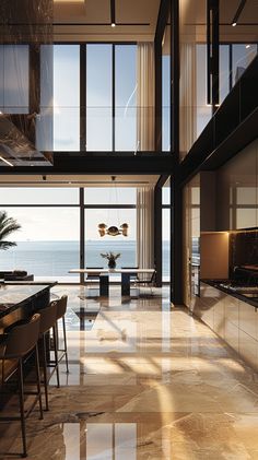 a large open living room and dining area next to the ocean