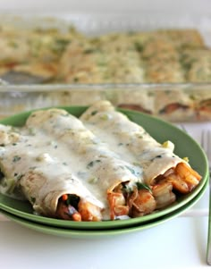 a green plate topped with enchiladas next to a casserole dish