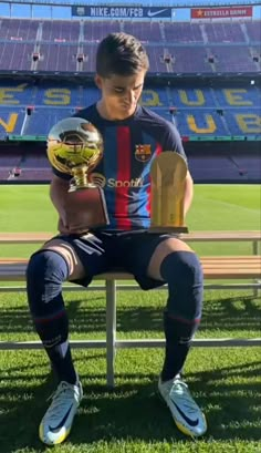 a young man sitting on top of a bench holding a soccer ball in his hand