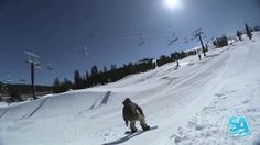 a man riding a snowboard down the side of a snow covered ski slope on a sunny day