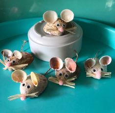 four little mice sitting on top of each other near some seashells and one is looking at the camera