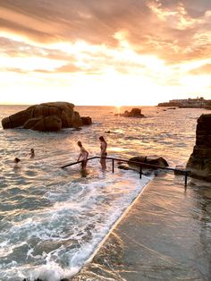 people are swimming in the ocean at sunset