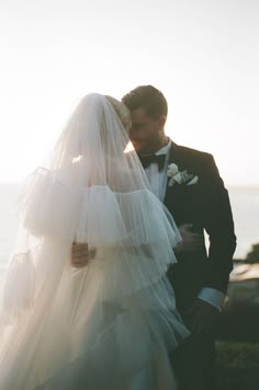 a bride and groom kissing in front of the ocean