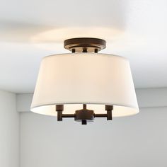 a light fixture with a white shade on it's ceiling in a living room