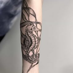 a black and white photo of a seahorse tattoo on the left arm with an octopus in it