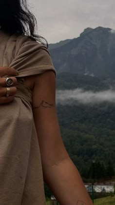 a woman with her arm wrapped around the back of her body and mountains in the background