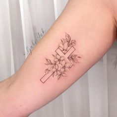 a woman's arm with a cross and flowers tattoo on the back of her left arm