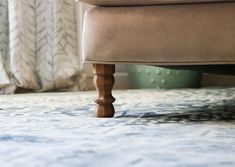 a close up view of a footstool on a carpeted floor with curtains in the background