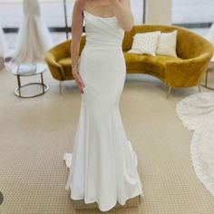 a woman in a white dress taking a selfie with her cell phone while standing in a living room