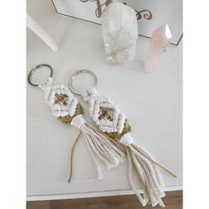 two white tasselled key chains sitting on top of a table next to crystals