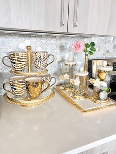 a kitchen counter topped with gold dishes and cups