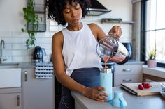 a woman is pouring something into a blender