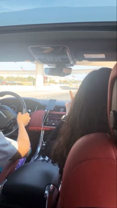 two people sitting in a car with the driver's seat up and steering wheel down