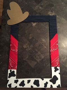 a cow print frame with a paper heart on the top and an arrow in the middle