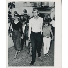 an old black and white photo of people walking down the street