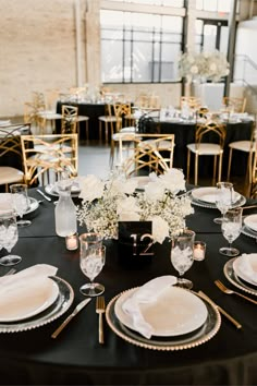 a table set with plates, silverware and white flowers in vases on it