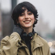 a woman with short hair wearing headphones on her ears and smiling at the camera