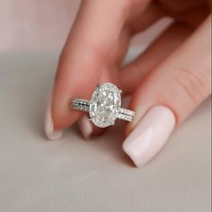 a woman's hand with a ring on her finger and an oval shaped diamond in the middle