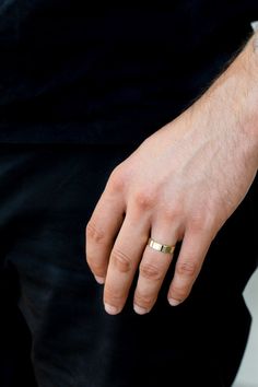 a close up of a person's hand with a gold ring on their finger