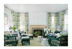 a living room filled with furniture and a fire place in front of a window covered in green curtains