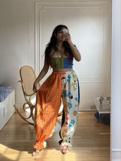 a woman standing in a room taking a photo with her cell phone and drinking from a cup