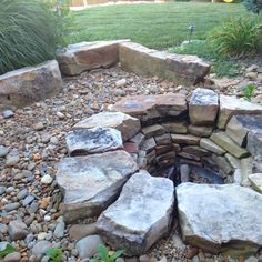 an outdoor fire pit surrounded by rocks and gravel