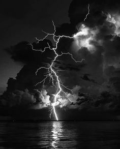 black and white photograph of lightning striking over the ocean