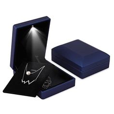 an open jewelry box with a necklace in it and a light shining on the inside