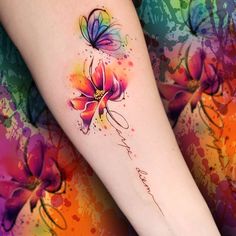 a woman's arm with watercolor flowers on it and the word love written in cursive writing